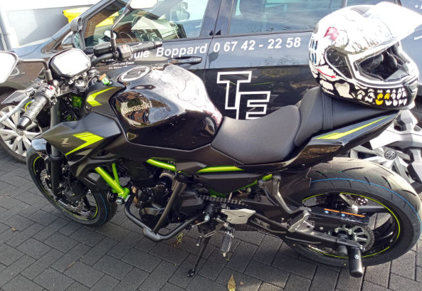 Kawasaki Z650 in Schwarz-Neongrün mit Fahrschul-Fahrzeug im Hintergrund